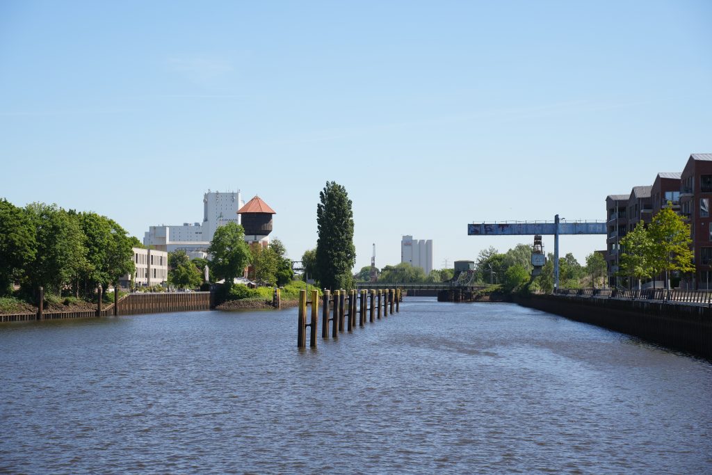 Das Bild zeigt die Aussicht auf den Kanal in Oldenburg. Im Hintergrund sind der alte Wasserturm und die Eisenbahnbrücke zu erkennen. Beides kann man vom Seminarraum aus sehen.